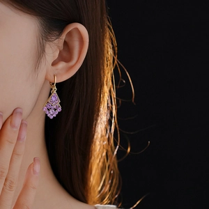 Close-up of diamond-encrusted rhombic leaf earrings with purple gems on a model