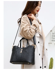Detail of black crocodile embossed handbag with metal lock and detachable strap on model