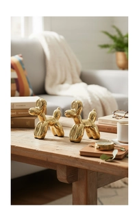 Set di due cani palloncino in ceramica dorata su un tavolino da caffè in legno
