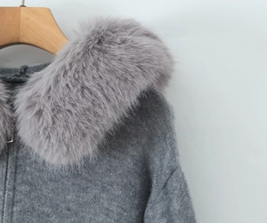 Close-up of a gray knit cardigan featuring a plush faux fur collar and zipper detail