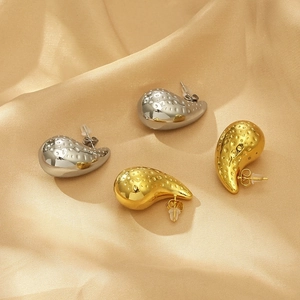 Detail shot of hollow teardrop earrings with hammered texture on gold satin background