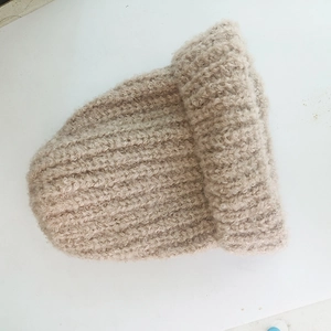 Detail shot of chunky knit texture and soft rolled edge on beige winter earflap hat