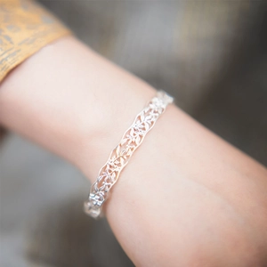 Macro shot of 925 sterling silver cuff bracelet with intricate hollow floral leaf pattern