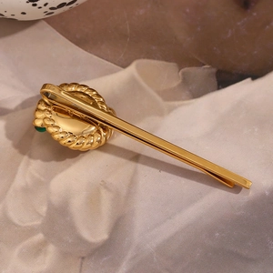 Detail of vintage 18K gold plated hair clip with twisted texture and green gemstone