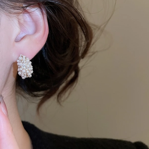 Macro detail of French vintage C-shaped hoop earrings with pearls and zircons on earlobe