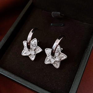 Macro shot of silver star stud earrings featuring intricate cross engraving and zircons