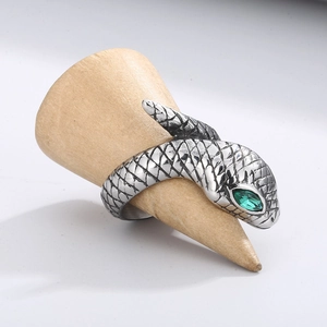 Vintage stainless steel snake ring with green stone eyes on a wooden display stand