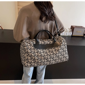 Dettaglio borsa da viaggio con jacquard geometrico bianco e nero e manici in pelle