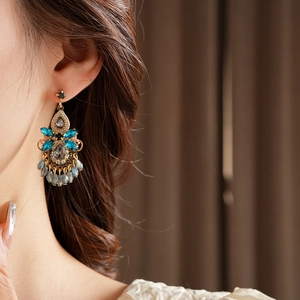 Close-up of vintage gold tassel earrings with dark grey stones and light blue crystal beads