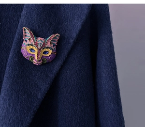 Detail of colorful bohemian cat head brooch with crystals on dark blue coat