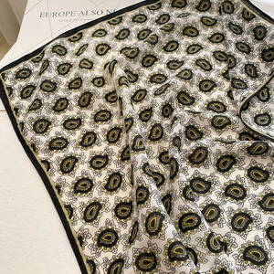 Detail shot of paisley patterned silk scarf with elegant black border and draped texture