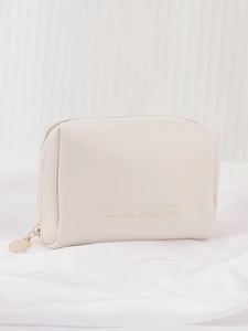 Detailed close-up of cream PU cosmetic bag with gold heart zipper and star text