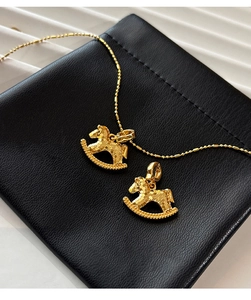 Detailed view of 18k gold plated rocking horse pendants on a black leather pouch