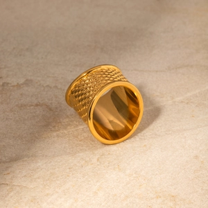 Macro shot of gold-plated wide ring with textured honeycomb hammered metal finish