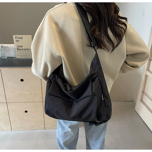 Detail view of a black large capacity canvas tote bag worn over the shoulder by a model