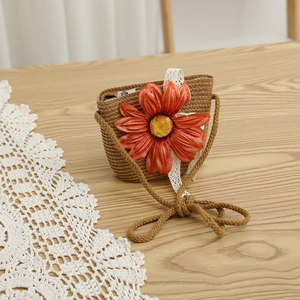Vue macro d'un mini sac en paille tressée avec grande fleur en soie et dentelle