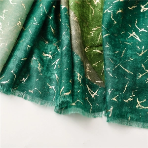 Macro detail of green gradient scarf with golden foil texture and fringe edges