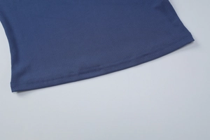 Détail des coutures de l'ourlet en maille côtelée sur un t-shirt bleu marine à col carré