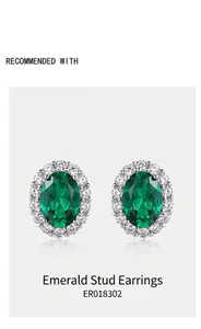 Macro shot of oval-cut emerald stud earrings with a sparkling halo of white diamonds