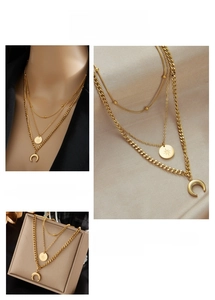 Détails des colliers dorés superposés avec pendentifs étoile et lune sur soie