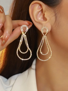 Macro detail of luxury long gold drop earrings with sparkling rhinestones on model