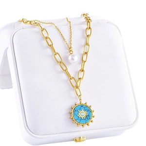 Double-layer gold necklace with sun turquoise pendant and white pearl on a jewelry box