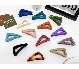 Detailed view of matte triangle hair claws in various colors on a clean white background
