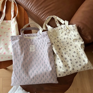 Three minimalist floral print canvas tote bags set on a rustic leather sofa background