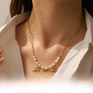 Detail view of gold starfish charms and white faux pearls on a delicate link chain necklace