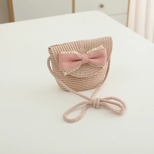 Close-up of pink straw woven crossbody bag with large polka dot bow and lace trim