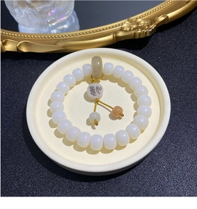 Macro shot of white bodhi seed bracelet with Joy pendant on ceramic tray