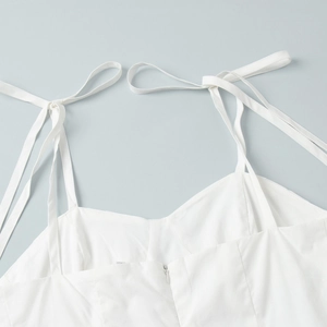 Détail d'une robe en coton blanc avec bretelles à nœuds et fermeture éclair au dos