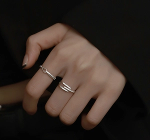 Close-up of silver knot and multi-layer zircon rings on finger with elegant detail
