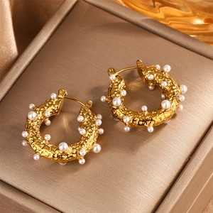 Detail of 18K gold plated hammered metal earrings with inlaid pearls on silk fabric