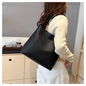 Model wearing a large black woven tote bag, showcasing casual oversized commute style