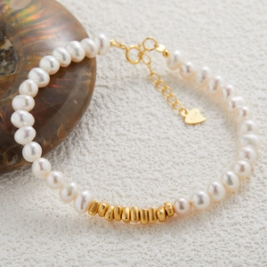 Macro shot of S925 sterling silver beads and natural freshwater pearls on a golden bracelet