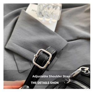 Detail of adjustable black leather shoulder strap with silver rectangular metal buckle