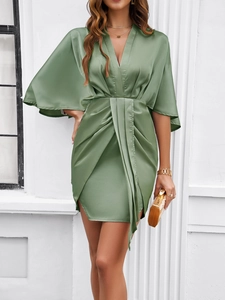Detail of green satin dress featuring deep V-neck, batwing sleeves and waist twist design