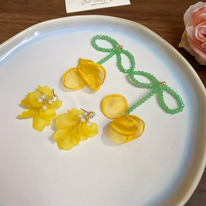 Dettagli di orecchini a fiore giallo opaco con perle e nappa di perline verdi
