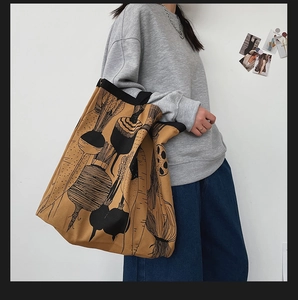 Minimalist camel canvas tote bag featuring artistic black vegetable print shown on shoulder