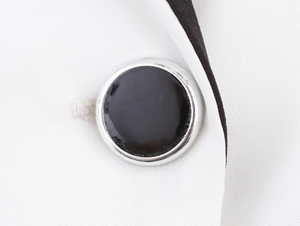 Détail d'un tissu tissé blanc avec un bouton noir et une bordure métallique argentée