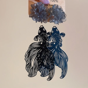 Detail of resin flower earrings with hollow metal carp pendants in dark blue and black