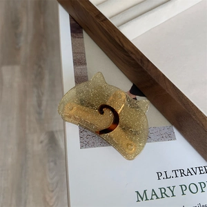Detail of cat shaped hair claw clip with golden glitter and semi-circular acetate design