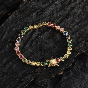 Colorful heart-shaped crystal tennis bracelet in gold finish on charcoal background