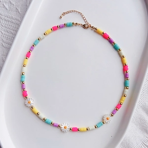 Detail of bohemian daisy beaded necklace with colorful clay discs and gold lobster clasp