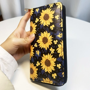 Detail of sunflower print long PU leather wallet with zipper closure and black background