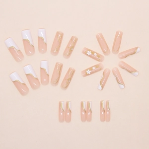 Detail of press-on nails featuring 3D gold daisies, pearls, and French white tips
