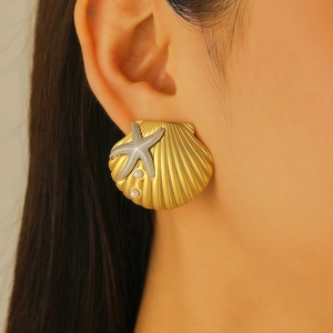 Close-up of a model wearing a gold shell and starfish earring with a pearl accent