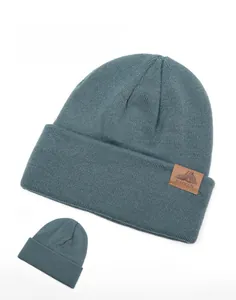 Detail of grey-blue knit beanie showing soft texture and brown leather mountain logo patch