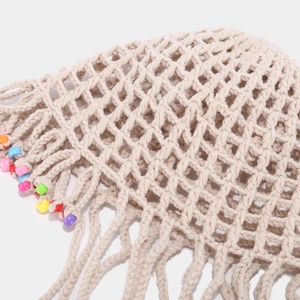 Détail d'un chapeau de plage beige au crochet avec perles colorées et pompons